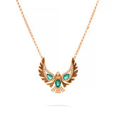 A rose gold necklace with a winged pendant featuring green emerald-cut stones and small clear accent stones, shown on a white background.